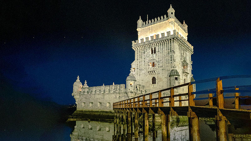 The Belém Tower illuminated at night.